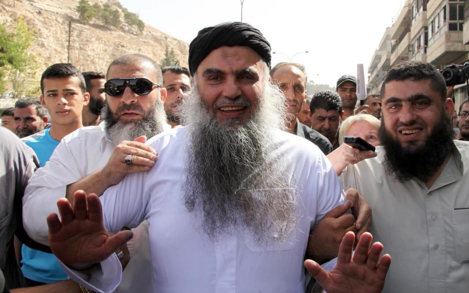 Abu Qatada is escorted through a crowd outside a court in Amman, Jordan in September 2014