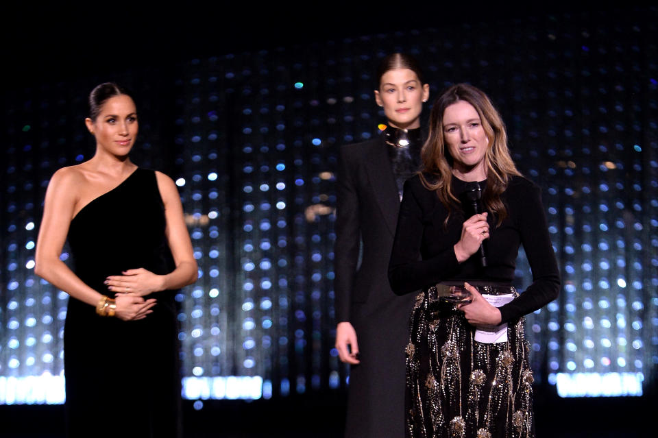 Clare Waight Keller with Meghan Markle and Rosamund Pike speaks on stage after receiving the award for British Womenswear Designer of the Year during The Fashion Awards in 2018. - Credit: Courtesy Photo