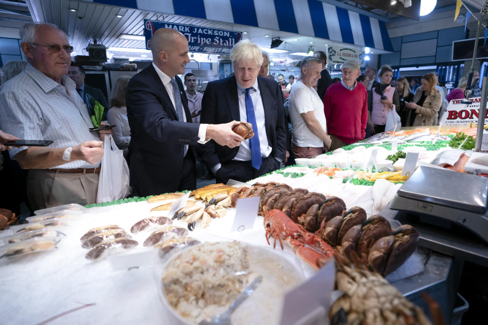 Britain's Prime Minister Boris Johnson, center left, speaks with Northern Powerhouse minister Jake Berry, second left, as they stop at a fishmongers during a visit to Doncaster Market, in Doncaster, Northern England, Friday Sept. 13, 2019. Johnson will meet with European Commission president Jean-Claude Juncker for Brexit talks Monday in Luxembourg. The Brexit negotiations have produced few signs of progress as the Oct. 31 deadline for Britain’s departure from the European Union bloc nears. ( AP Photo/Jon Super)