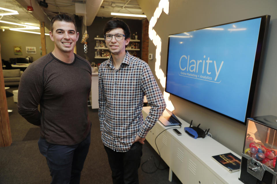 In this Tuesday, Sept. 10, 2019, photo Shane Griffiths, right, and Trenton Erker, left, co-owners of the digital marketing company Clarity Online, pose for a photo in Seattle. Griffiths and Erker use technology for tasks like billing, scheduling appointments, tracking the time they spend on clients' projects and putting together reports on visits to client websites, as well as using freelancers for other tasks as ways to save money on employment costs, and also have more flexibility when they need specific talents or expertise for a project. (AP Photo/Ted S. Warren)