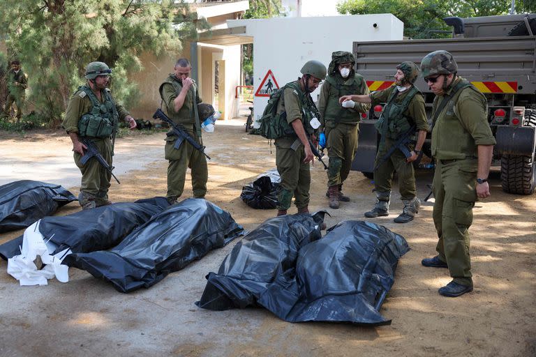 Soldados israelíes se preparan para retirar los cuerpos de sus compatriotas, muertos durante un ataque de militantes palestinos, en Kfar Aza, al sur de Israel, en la frontera con la Franja de Gaza