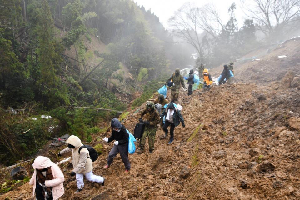 日本石川縣輪島市部分道路在強震後受損嚴重，自衛隊成員協助偏遠地區居民撤離。路透社