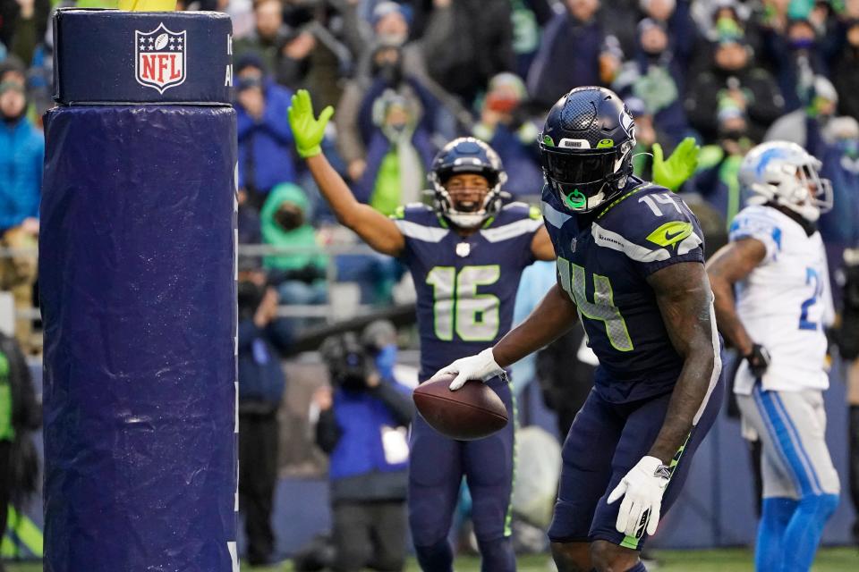 Seattle Seahawks wide receiver DK Metcalf (14) holds the football as wide receiver Tyler Lockett (16) reacts after Metcalf scored a touchdown against the Detroit Lions during the second half of an NFL football game, Sunday, Jan. 2, 2022, in Seattle. (AP Photo/Elaine Thompson)