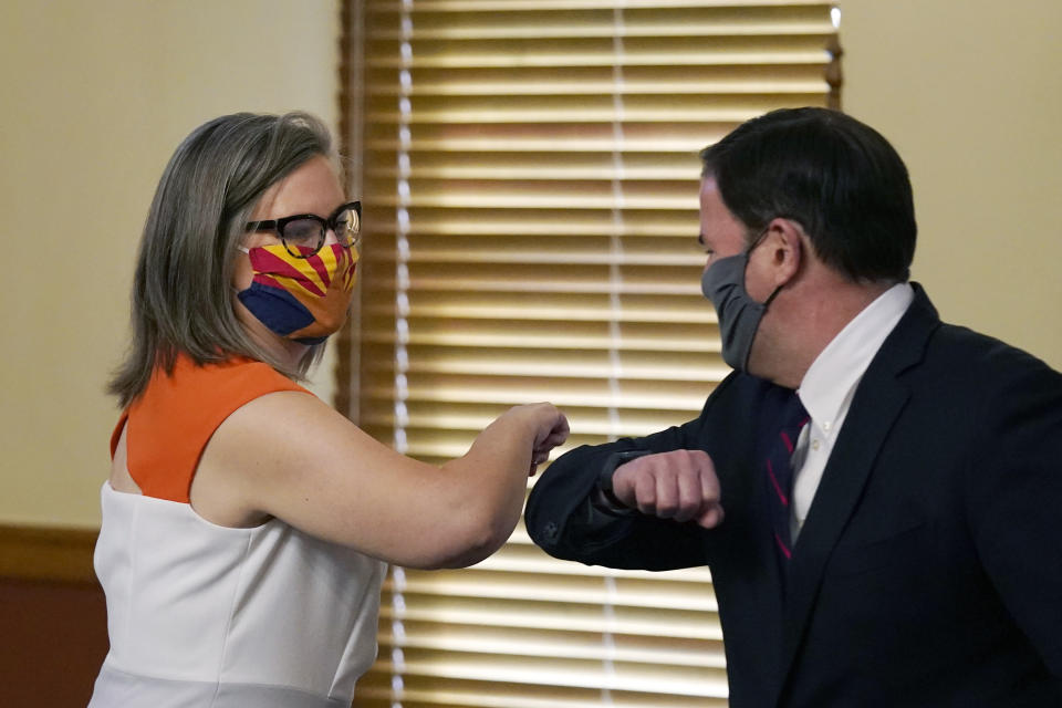 Arizona Secretary of State Katie Hobbs, left, and Arizona Gov. Doug Ducey bump elbows as they meet to certify the election results for federal, statewide, and legislative offices and statewide ballot measures at the official canvass at the Arizona Capitol Monday, Nov. 30, 2020, in Phoenix. (AP Photo/Ross D. Franklin, Pool)