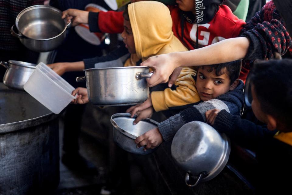 Palestinian children wait to receive food cooked by a charity kitchen amid shortages of food supplies, as the conflict between Israel and the Palestinian Islamist group Hamas continues, in Rafah, in the southern Gaza Strip on March 5, 2024.