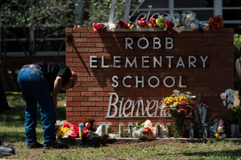 A law enforcement officer lights a candle outside Robb Elementary School in Uvalde, Texas, on Wednesday.