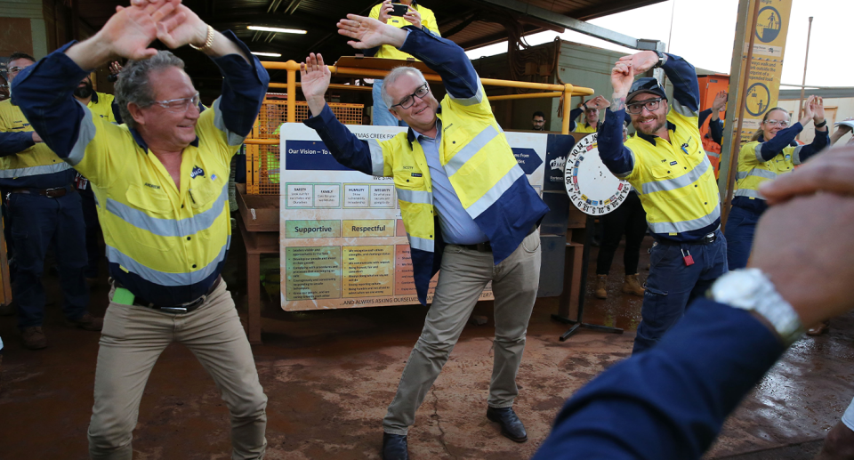 Scott Morrison next to the Fortescue Metals Group CEO at mine in the Pilbara. They are stretching.