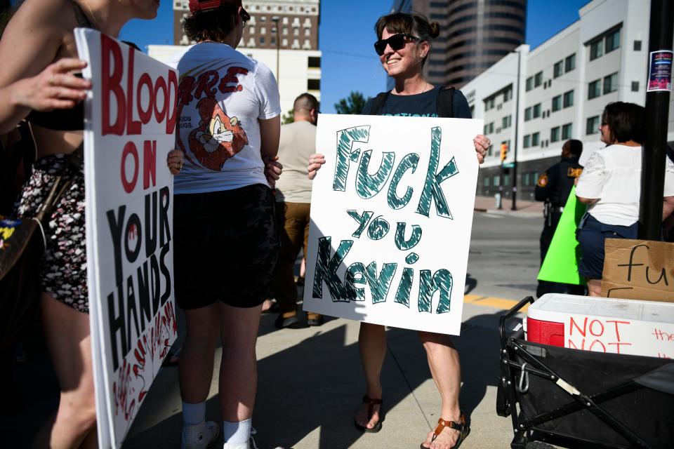 People hold hand-written signs.