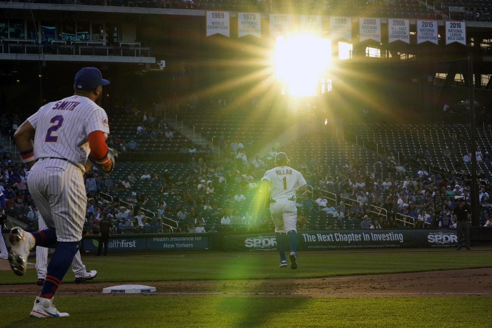 New York Mets players, including Dominic Smith (2) left, and Mets third baseman Jonathan Villar (1) take their positions during a baseball game against the Chicago Cubs as sun streams into the stadium, Thursday, June 17, 2021, in New York. (AP Photo/Kathy Willens)