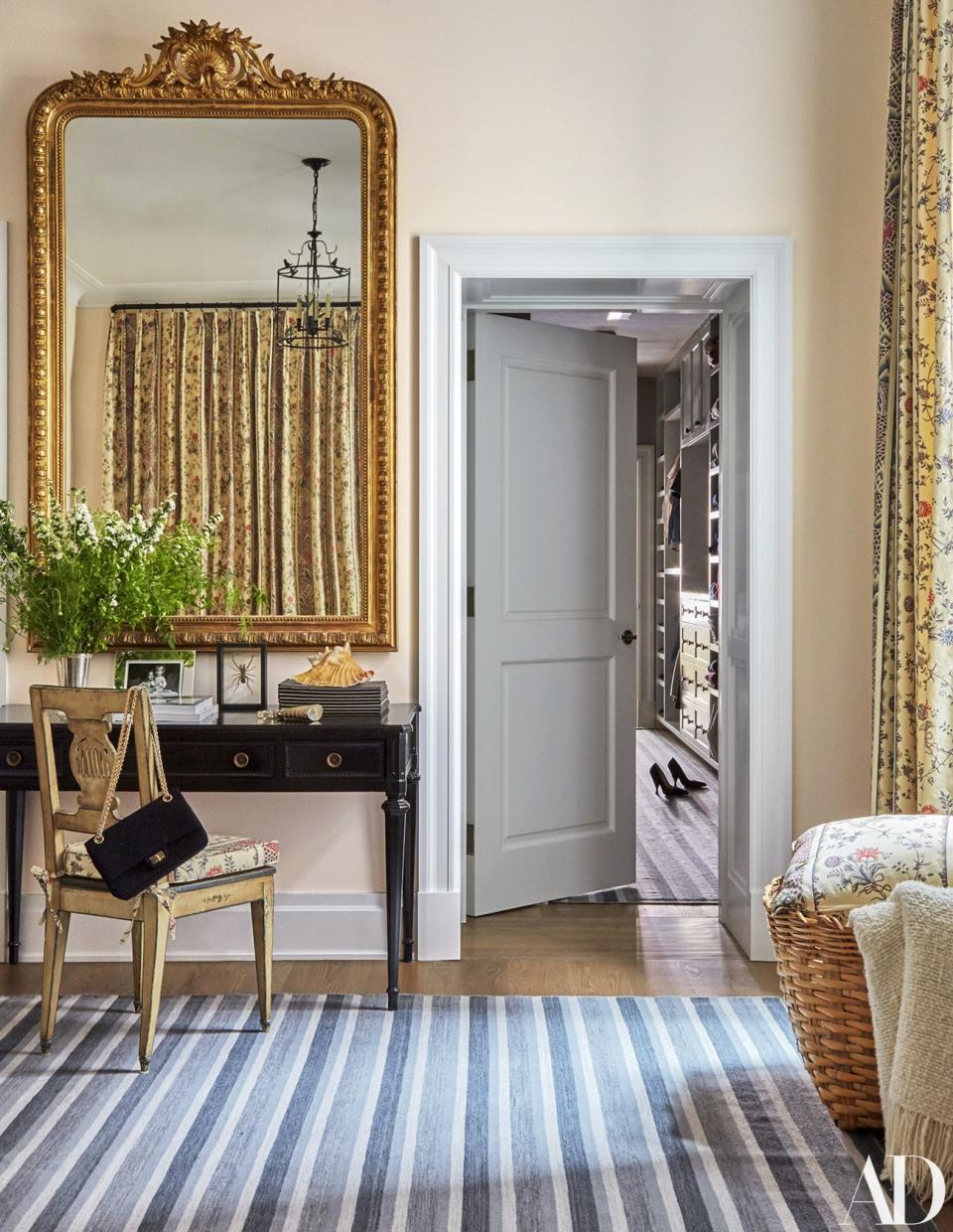 A 1940s desk and antique chair sit below a 19th-century giltwood mirror in the master bedroom. Rug by Crosby Street Studios.