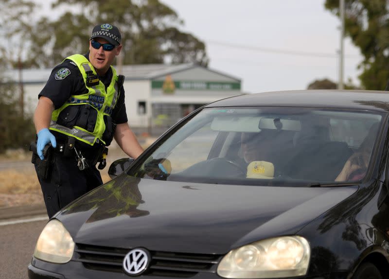 Motorists fill out paperwork for police as they cross back into South Australia from Victoria during the coronavirus disease (COVID-19) outbreak, in Bordertown