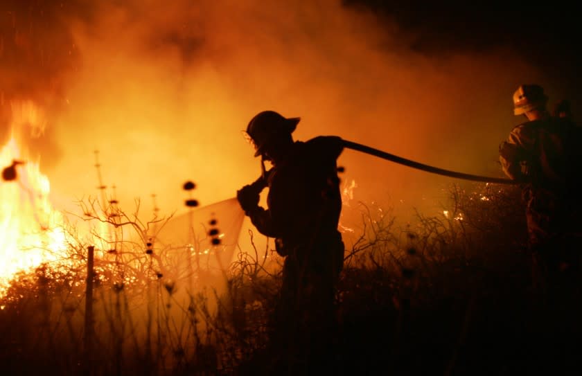 A firefighter hoses flames spread by Santa Ana winds in 2007.