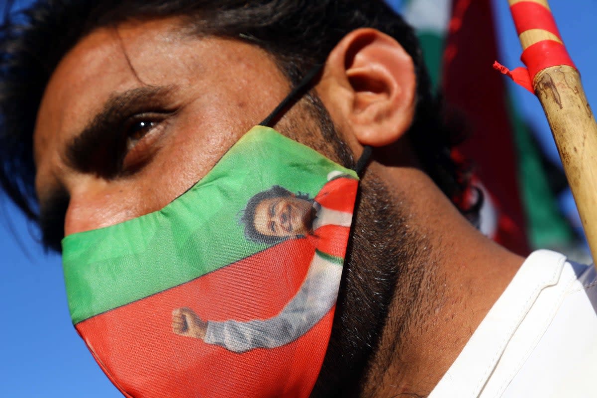 A supporter of the Pakistan Tehrik-e-Insaf (PTI) political party wears a facemask with the picture of party leader Imran Khan, during a protest against alleged rigging in the general election (EPA)