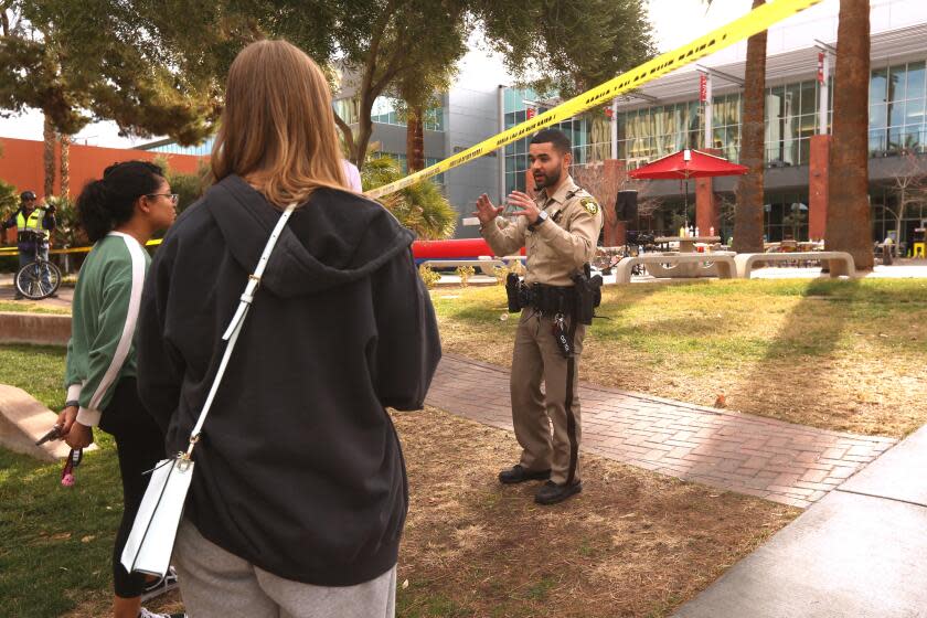 LAS VEGAS, NV - DECEMBER 7, 2023 - A police officer talks with students near the Student Union, background, a day after three people died and one person was injured in a mass shooting at the UNLV campus on December 7, 2023. (Genaro Molina / Los Angeles Times)