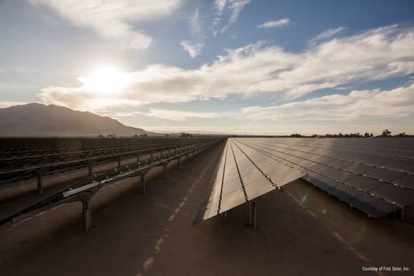 Large, utility scale thin-film solar installation by First Solar in the desert with partly cloudy skies in the background.