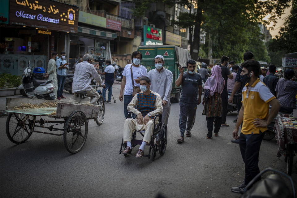 An Afghan refugee pushes a wheelchair through a market in New Delhi, India on Aug. 17, 2021. For thousands of Afghan refugees living in India, their plans to someday return home were dashed by the Taliban's shockingly swift takeover of the country. Some refugees struggle to put food on the table. Others are trapped in a complex bureaucratic process to register as refugees. What many thought would be a short, temporary escape has turned into a never-ending exile. (AP Photo/Altaf Qadri)