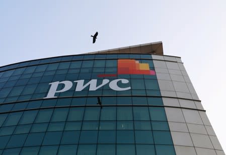 A bird flies past the logo of Price Waterhouse installed on the facade of its office in Mumbai