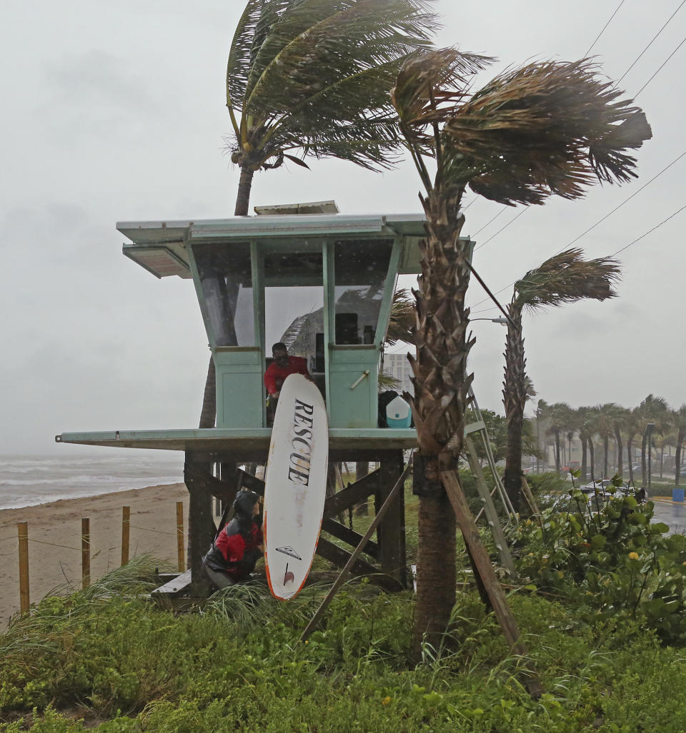 Dania Beach, Fla., Ocean Rescue Alice Henley and Dillon Wise secure their surfboard as Tropical Storm Gordon pass by South Florida with wind gust and heavy rainfall on Monday, Sept. 3, 2018. (David Santiago/Miami Herald via AP)