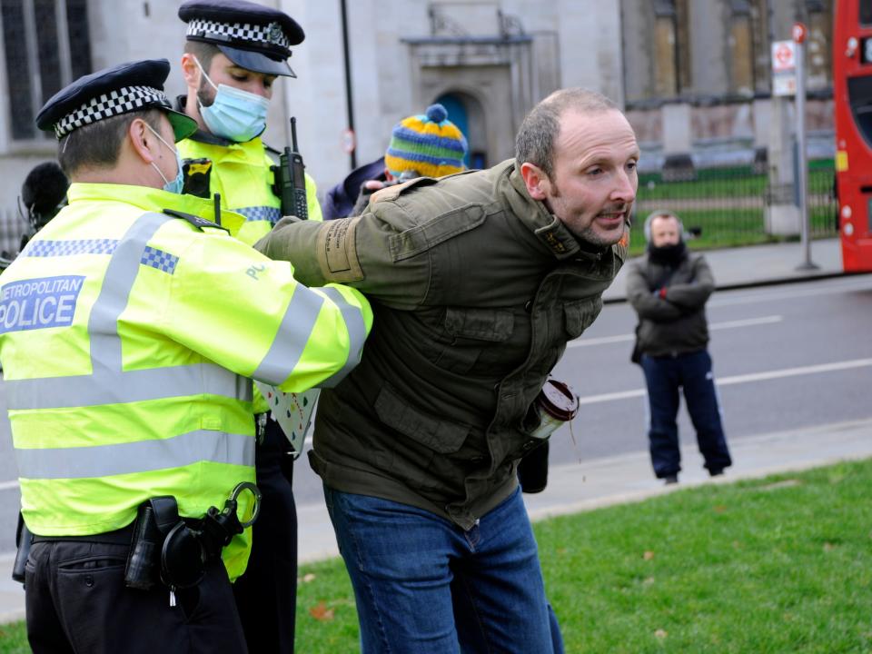 <p>A demonstrator is apprehended at an anti-lockdown protest in central London</p> (Rex Features)