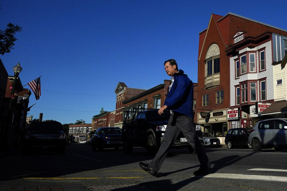 A man walks through downtown Skowhegan, Maine, Tuesday, Sept. 14, 2021. The town has relied on waterpower for its milling industries since the nineteenth century. Conservation groups are advocating for the removal of dams which provide power to a nearby paper mill. (AP Photo/Robert F. Bukaty)