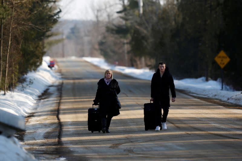 FILE PHOTO: People walk with their luggage on Roxham Road before crossing the US-Canada in Champlain