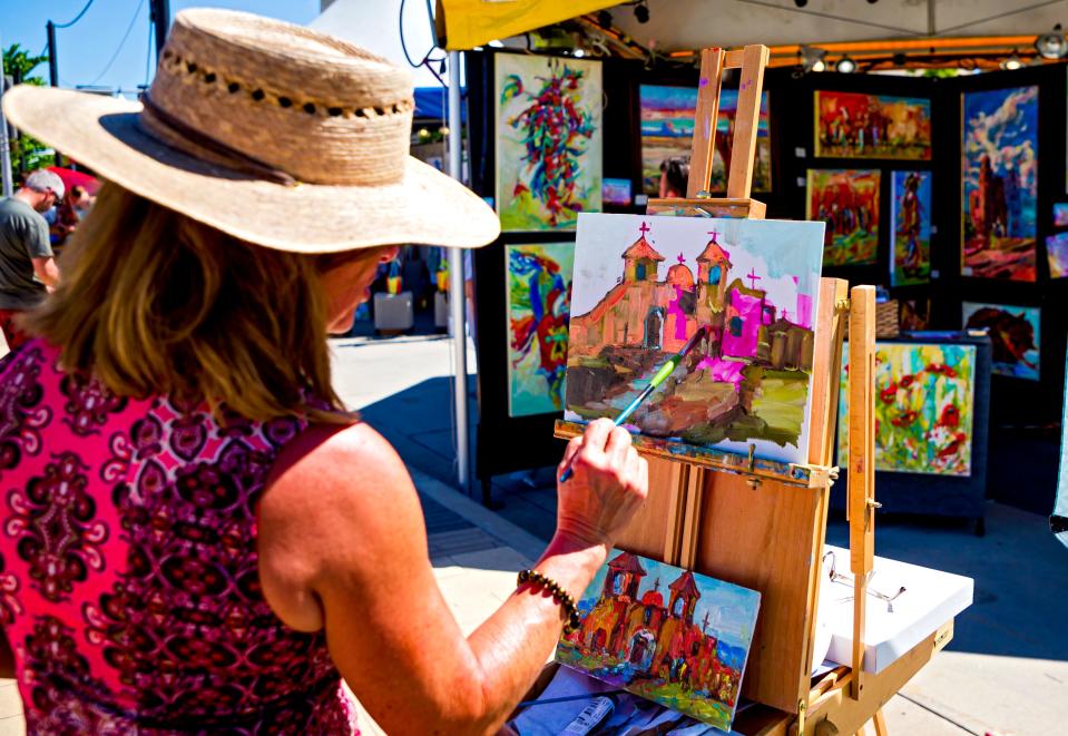 Artist Dawn Normali, of Colorado, paints some art work at her booth during the opening day of the 2021 Festival of the Arts in Bicentennial Park in Oklahoma City.