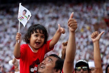 A man carries a girl on his shoulders as they attend a campaign rally of Indonesia's incumbent presidential candidate Joko Widodo at Gelora Bung Karno stadium in Jakarta, Indonesia, April 13, 2019. REUTERS/Willy Kurniawan