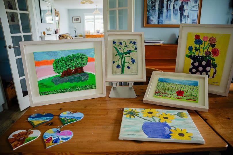 A series of paintings on display, standing on a table