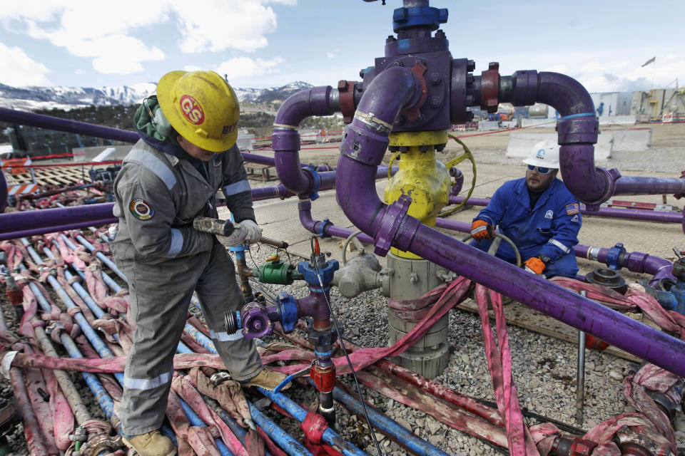 FILE - In this March 29, 2013 file photo, workers tend to a well head during a hydraulic fracturing operation at an Encana Oil & Gas (USA) Inc. gas well outside Rifle, in western Colorado. The vast majority of economists surveyed this month by The Associated Press say lifting restrictions on exports of oil and natural gas would help the economy even if it meant higher fuel prices for consumers. (AP Photo/Brennan Linsley, File)