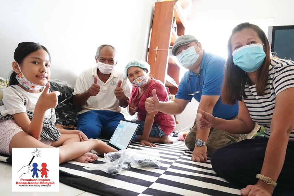 Noralisa Sofia Mohd Azeli (left) and her family members give a thumbs up to the new laptop. — Picture courtesy of Children’s Wish Society of Malaysia