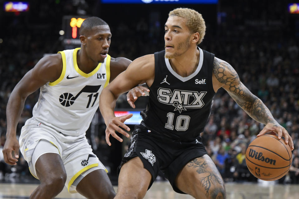 San Antonio Spurs' Jeremy Sochan (10) drives against Utah Jazz's Kris Dunn during the first half of an NBA basketball game Tuesday, Dec. 26, 2023, in San Antonio. (AP Photo/Darren Abate)