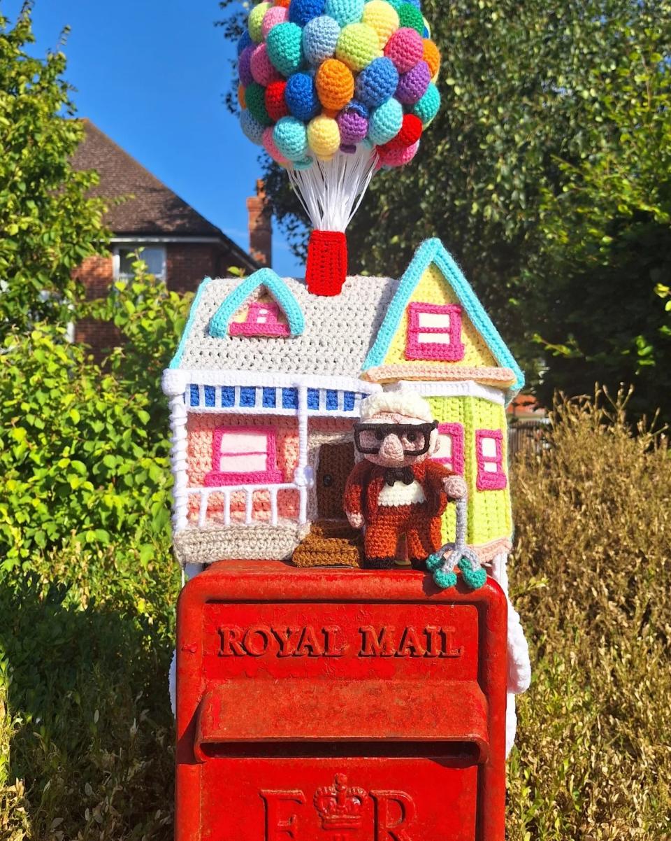 Crocheted house on top of a postbox 