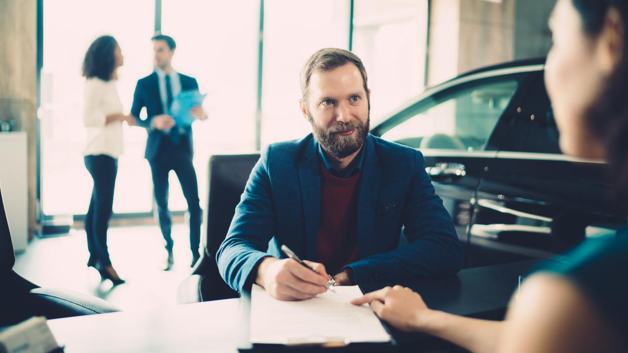 Businessman signing documents for buying luxury car.