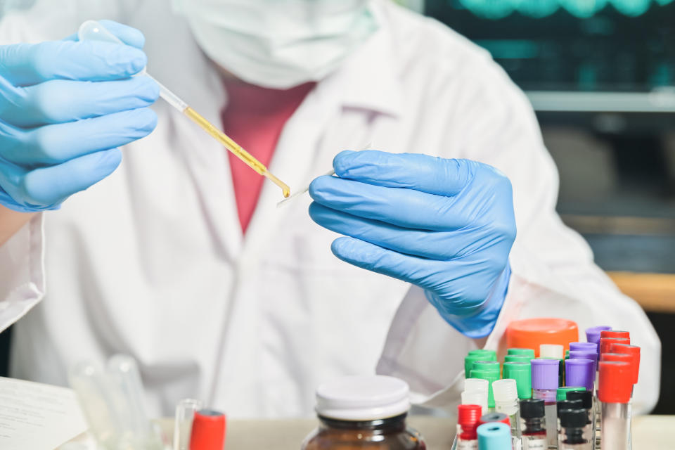 Medical Scientist hand holding specimen dropper to paper test in Laboratory room at hospital, blood test tube for analysis and diagnosis illness patient results.