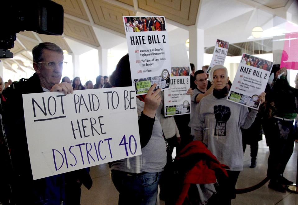 Opponents of HB2 hold signs outside the North Carolina House chambers gallery as the North Carolina General Assembly convenes for a special session at the Legislative Building in Raleigh, N.C. on Wednesday, Dec. 21, 2016. North Carolina's legislature reconvened Wednesday to decide whether enough lawmakers are willing to repeal a 9-month-old law that limited LGBT rights, including which bathrooms transgender people can use in public schools and government buildings. (Chris Seward/The News & Observer via AP)