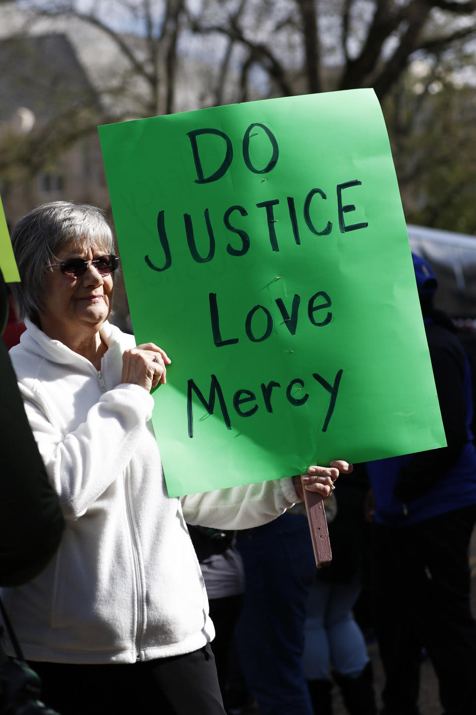 Martha Lightsey of Wesson, Miss., holds a homemade sign calling for justice, love and mercy at a mass gathering in front of the Mississippi Capitol in Jackson, Friday, Jan. 24, 2020, to protest conditions in prisons where inmates have been killed in violent clashes in recent weeks. (AP Photo/Rogelio V. Solis)
