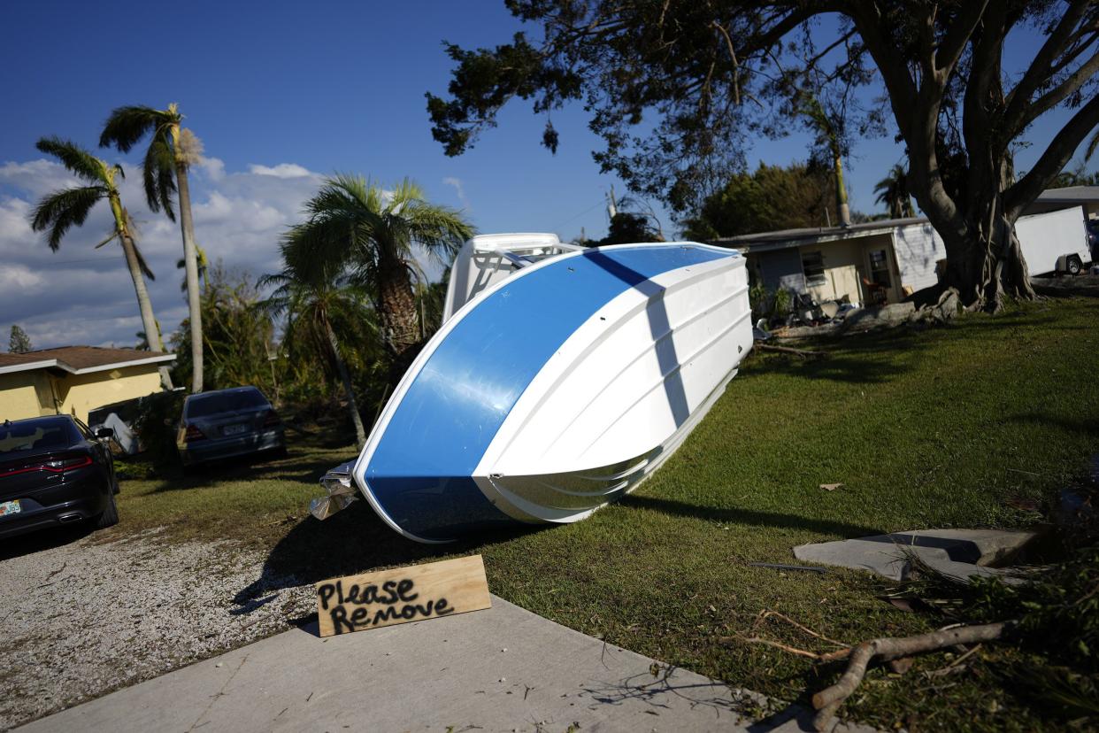 A sign placed by a resident asks that a boat that landed on their lawn during Hurricane Ian please be removed, in Fort Myers, Fla., Saturday, Oct. 1, 2022.