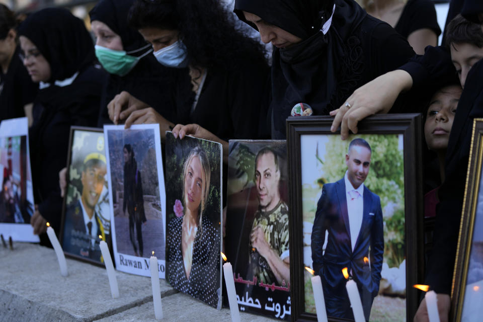 Relatives of victims of the Aug. 4, 2020, Beirut port explosion light candles and hold portraits of their loved ones, in Beirut, Lebanon, Sunday, July 4, 2021. A year after the deadly blast, families of the victims are consumed with winning justice for their loved ones and punishing Lebanon's political elite, blamed for causing the disaster through their corruption and neglect. (AP Photo/Hassan Ammar)