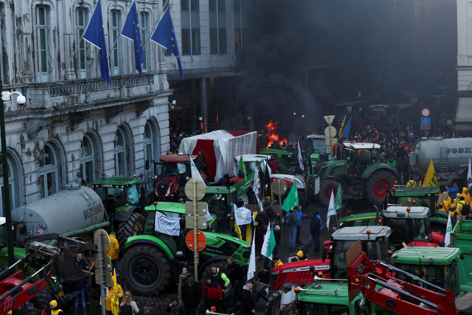 Smoke rises from a fire burning as farmers from Belgium and other European countries use their tractors to block the European Parliament, as they protest over price pressures, taxes and green regulation, in Brussels, Belgium February 1, 2024. REUTERS/Yves Herman