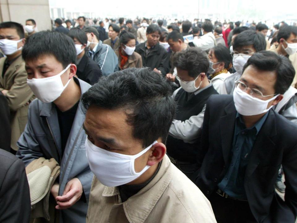 People wear masks as protection against the SARS virus as they wait to buy tickets at the Beijing Railway Station Wednesday, April 23, 2003.