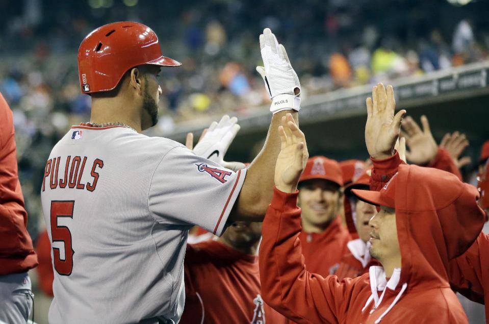 Los Angeles Angels' Albert Pujols (5) is congratulated in the dugout after hitting a three-run home run during the sixth inning of a baseball game against the Detroit Tigers in Detroit, Friday, April 18, 2014. (AP Photo/Carlos Osorio)