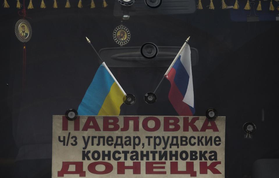 In this photo taken Tuesday, Feb. 25, 2014, the Russian and Ukrainians flags decorate windshield of a bus, in Donetsk, eastern Ukraine. If Ukraine looks neatly delineated on maps, its history is a tangle of invasions and occupations and peoples and religions, a place of ill-defined borders that for centuries has been struggling to define itself. The modern nation is so sharply divided by culture and loyalty, split between allegiance to Moscow and allegiance to Western Europe, that it often can appear ready to simply snap in two. (AP Photo/Darko Bandic)