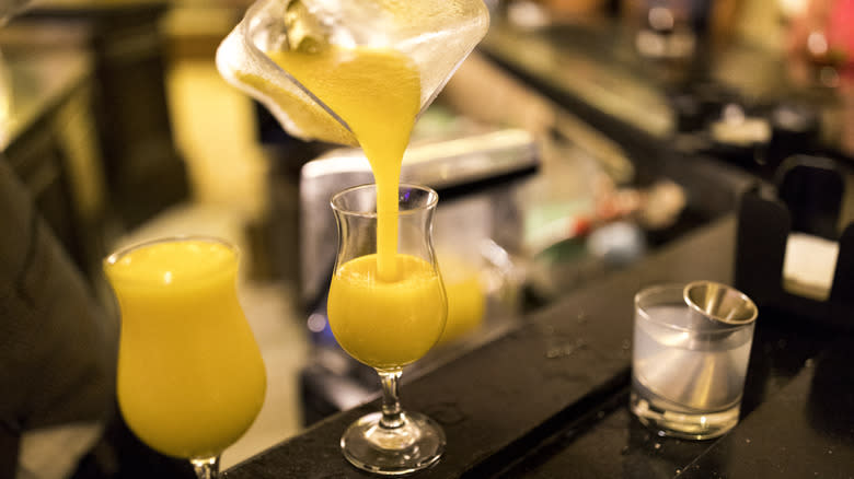 Person pouring blended spiked slushies into a tulip glass