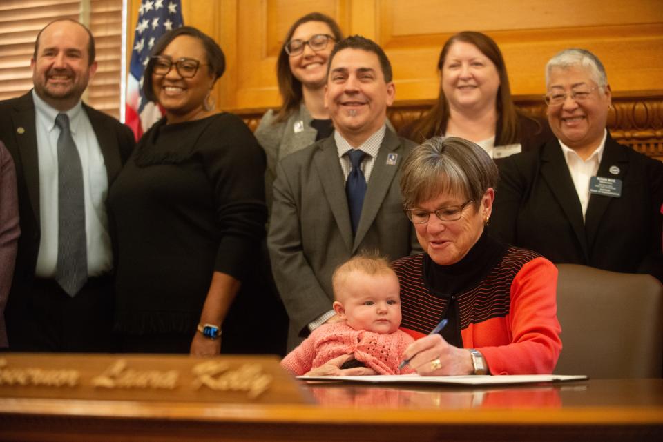 Gov. Laura Kelly signs an executive order to create a task force aimed at creating a government agency on child care while holder her granddaughter, four-month-old Laura "Rory" Janeway Weiden, alongside her daughter, Kathleen Daughety, Lt. Gov. David Toland, and cabinet members Tuesday at the Statehouse.