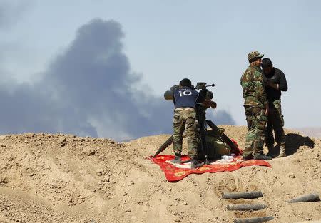 Smoke rises from the Ajil oil field as Shi'ite fighters gather in Al Hadidiya, south of Tikrit, en route to the Islamic State-controlled al-Alam town, where they are preparing to launch an offensive on Saturday, March 6, 2015. REUTERS/Thaier Al-Sudani