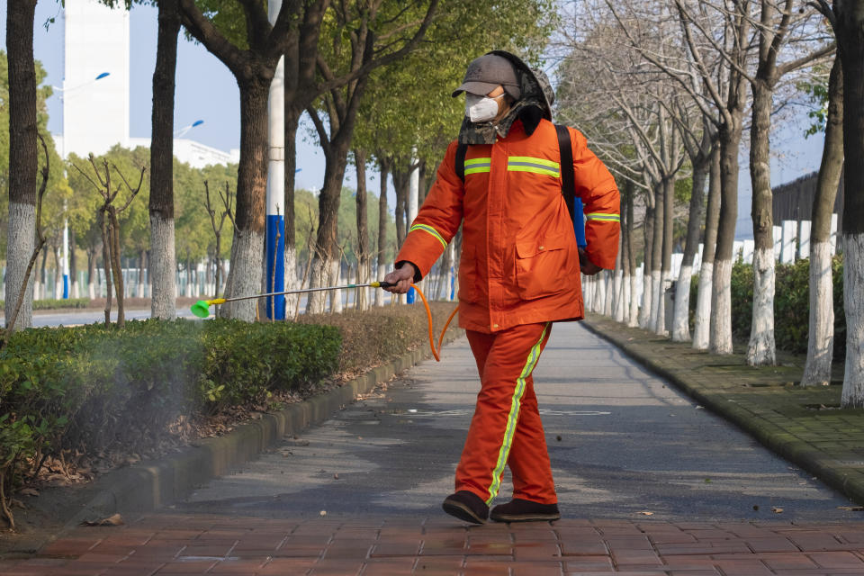 FILE - In this Tuesday, Jan. 28, 2020, file photo, a worker wearing a face mask sprays disinfectant along a path in Wuhan in central China's Hubei Province. Face masks are in short supply in parts of the world as people try to stop the spread of a new virus from China. Health officials recommend strap-on medical masks for people being evaluated for the new virus, their household members and caregivers. (AP Photo/Arek Rataj, File)