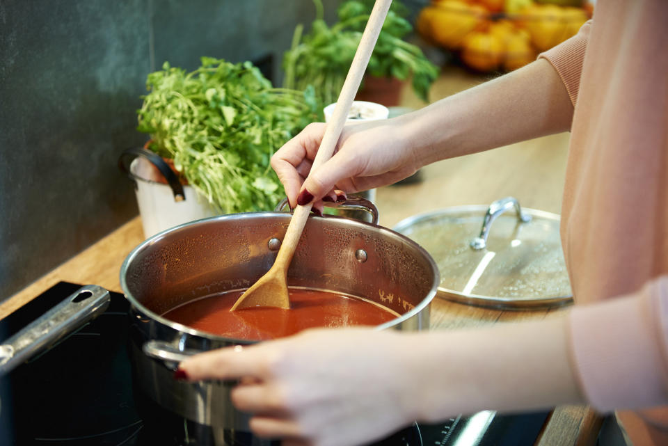 Person cooking tomato soup in kitchen