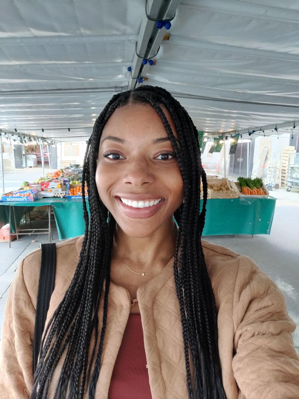 The author smiling in a market area with produce stands in the background