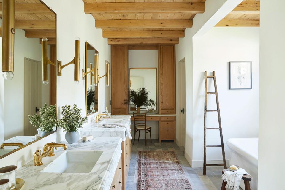 The main bathroom is the sole spot in the home where Lewis switched up the wall paint color, opting for Portola Paints’ Table Linen to eliminate any green undertones that could “look funky” on the skin. A Pinterest photo inspired the vanities with an apron front and Calacatta Super Oro Gold Vein marble on the countertops. Gold Waterworks fixtures, Lee Valley brass hardware, and custom oak cabinetry make the freestanding Waterworks Empire bathtub look especially inviting.