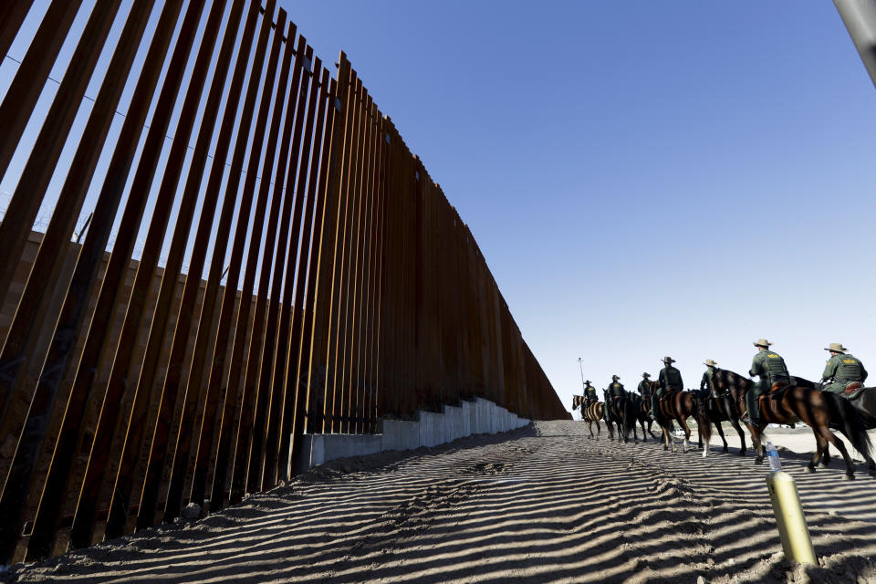 FILE - In this Oct. 26, 2018, file photo, mounted Border Patrol agents ride along a newly fortified border wall structure in Calexico, Calif. President Donald Trump is visiting Calexico on Friday, April 5, 2019, to tour the recently-built portion of the border fence that bears a silver plaque with his name on it. (AP Photo/Gregory Bull, File)
